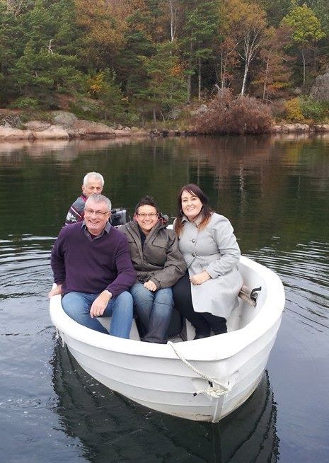 Four people sit in a white boat on a lake