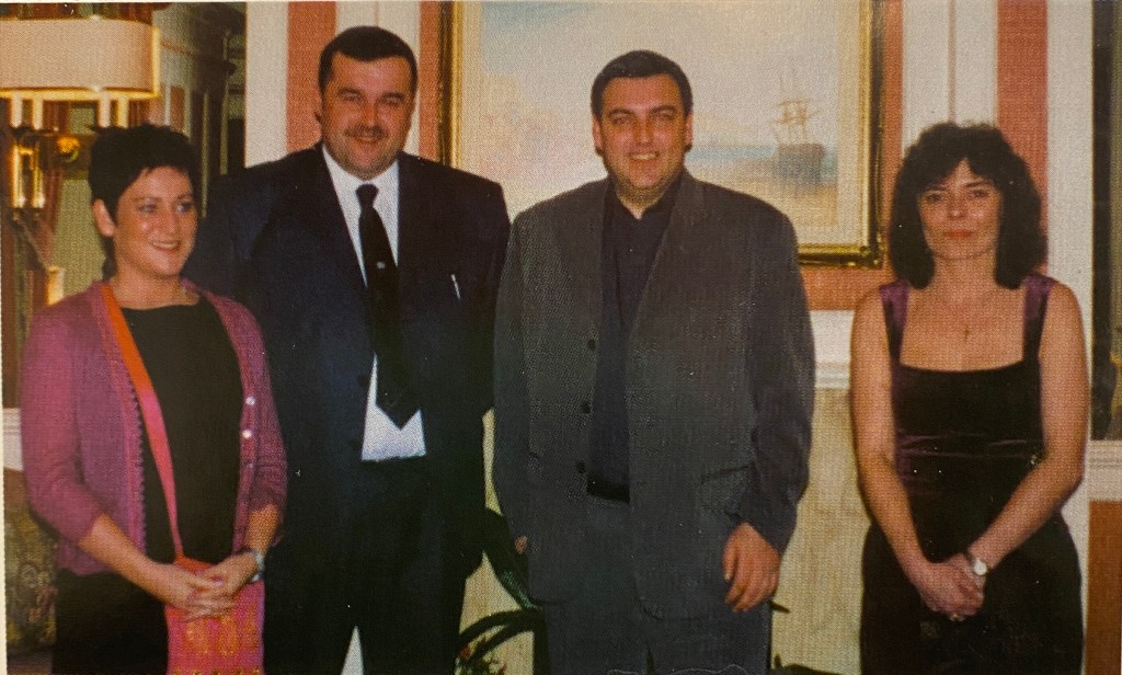 Two women and two men in smart clothing stand in a row smiling at the camera